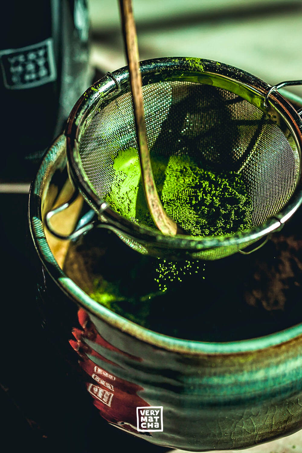 Matcha-Pulver wird durch ein Sieb in eine traditionelle Matcha-Schale gesiebt, um Klümpchen zu entfernen und die perfekte Textur für die Zubereitung zu erreichen