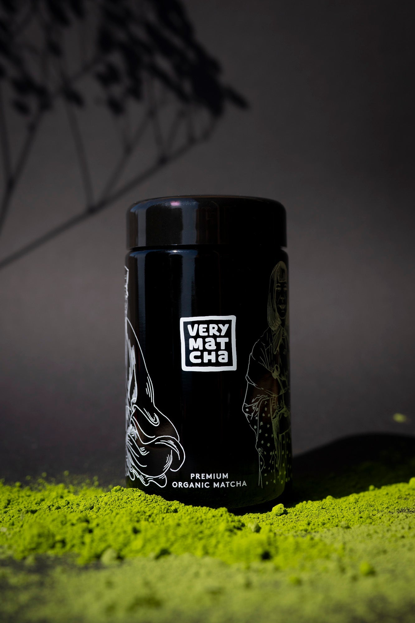 Very Matcha: Ceremonial Grade Premium Organic Matcha, umgeben von leuchtend grünem Matcha-Pulver auf dunklem Hintergrund