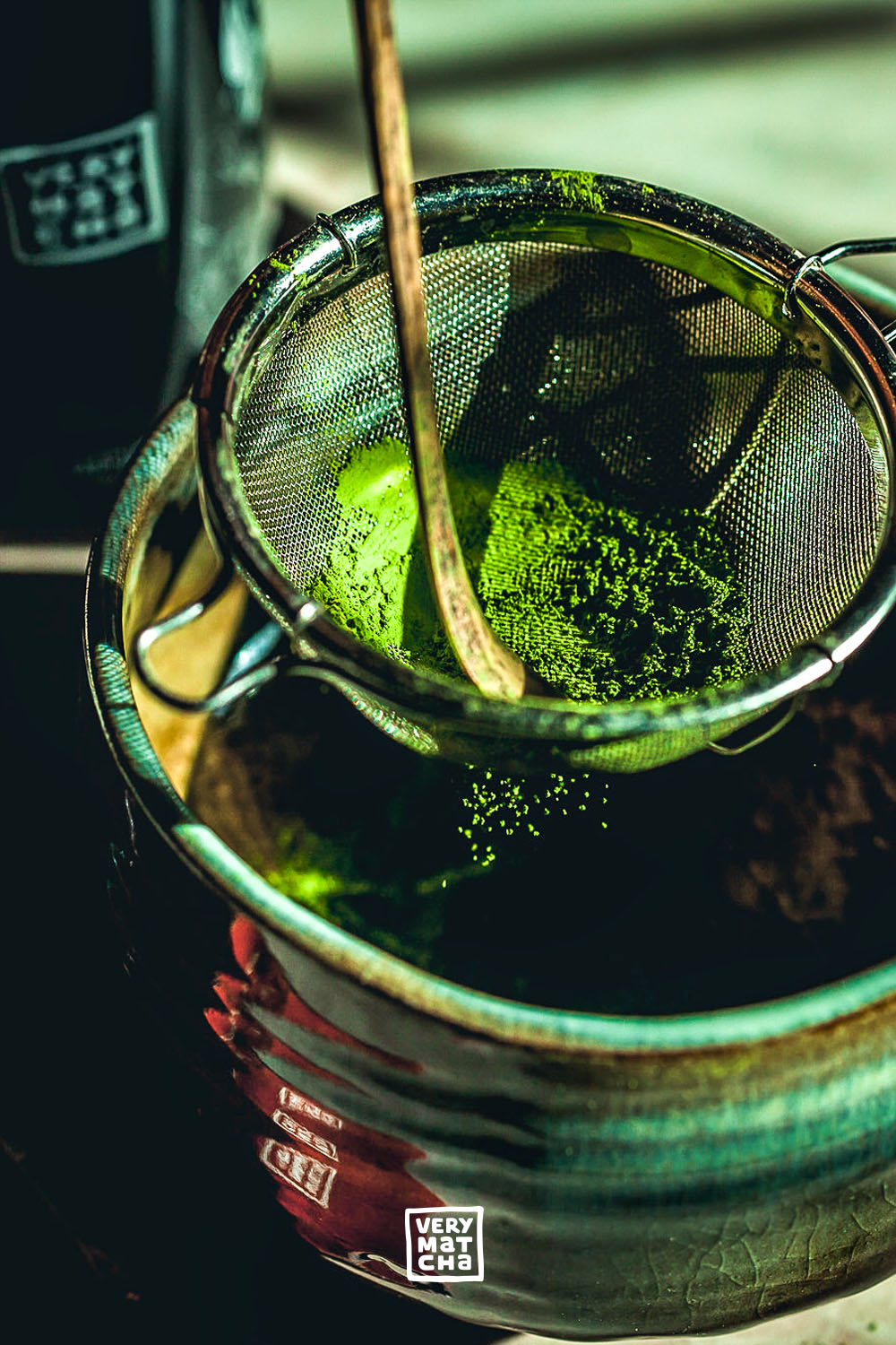 Matcha-Pulver wird durch ein Sieb in eine traditionelle Matcha-Schale gesiebt, um Klümpchen zu entfernen und die perfekte Textur für die Zubereitung zu erreichen