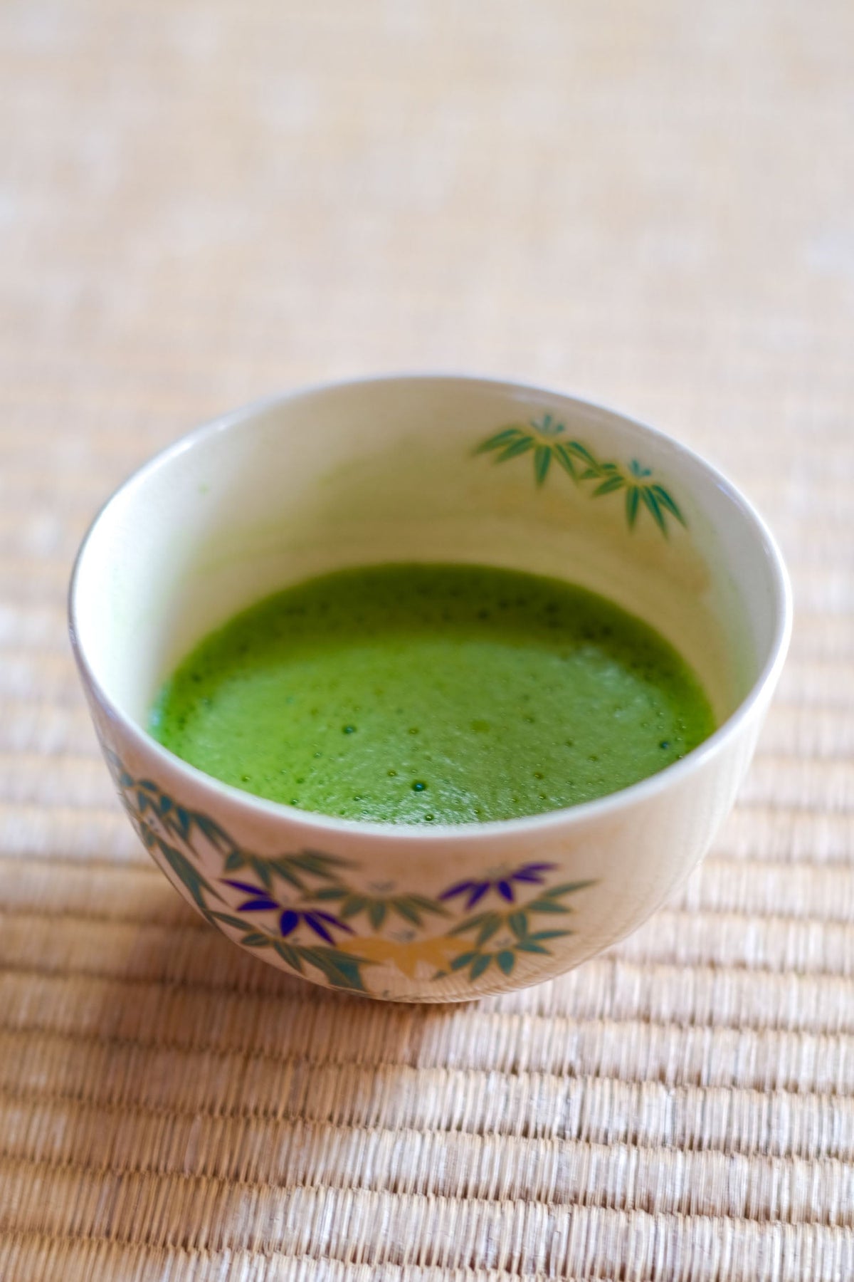 Nahaufnahme: Frisch aufgeschäumter Matcha mit feinem Schaum (Microfoam) serviert auf einer Tatami Matte in Kyoto, Japan